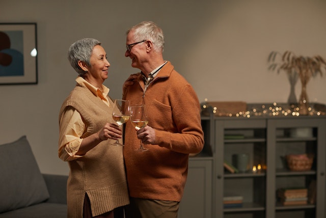 an elderly couple hugging and drinking wine